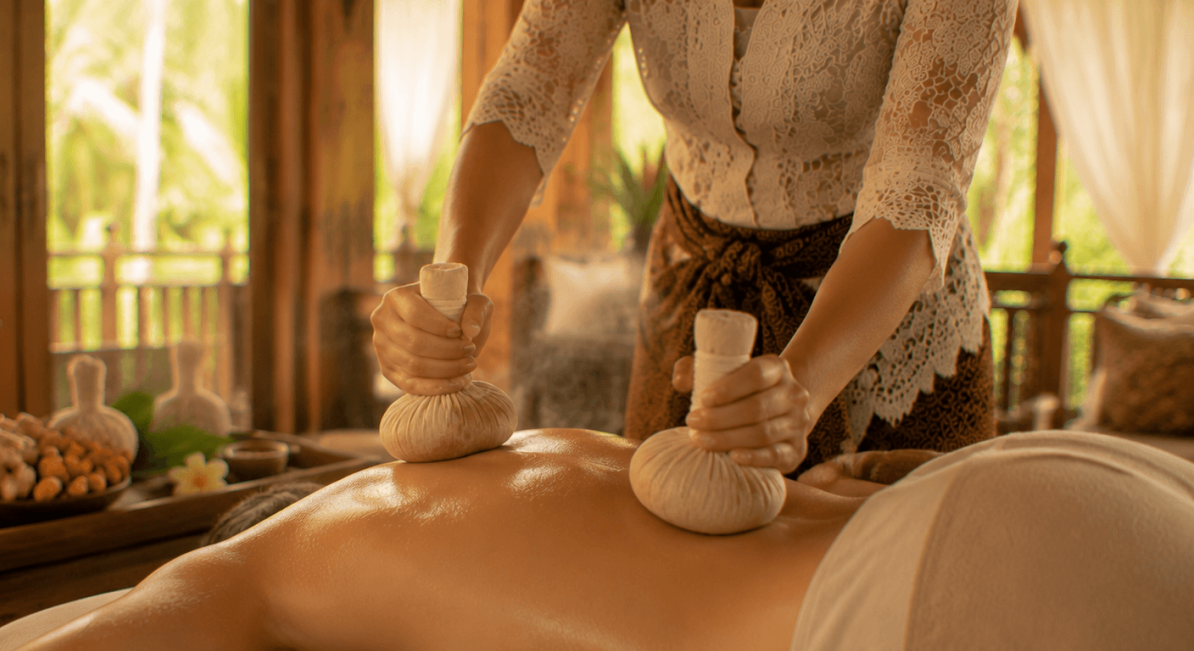 Therapist compres herbal ball for herbal massage treatment in villa bali