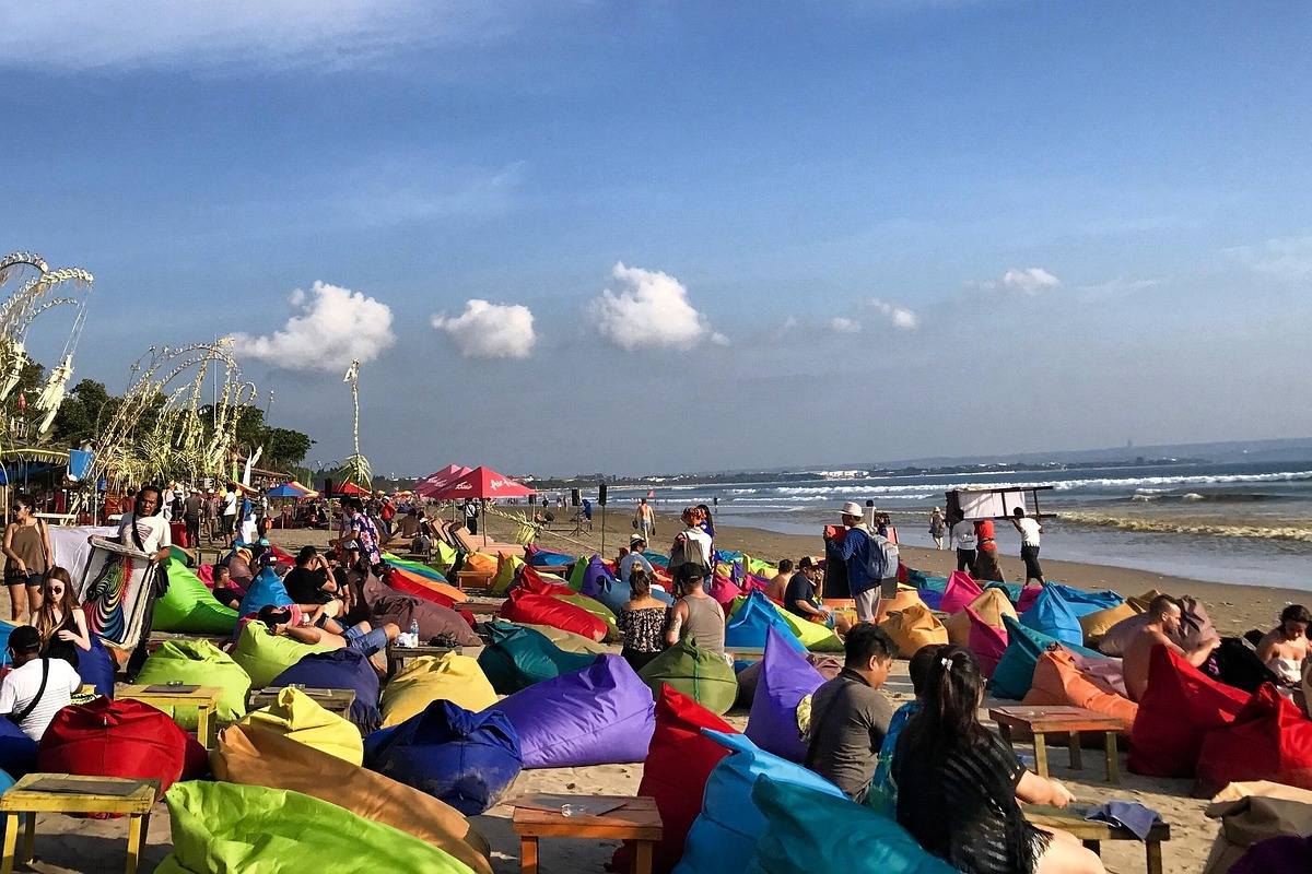 Tourists sit on comfortable beanbags at the water's edge, enjoying the afternoon atmosphere at Padma Beach, Seminyak.
